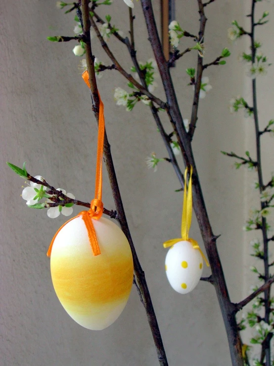 a yellow and white ornament hanging from a tree