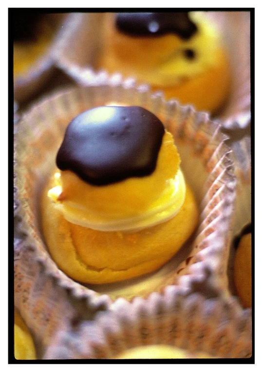 yellow cupcakes are decorated with black frosting