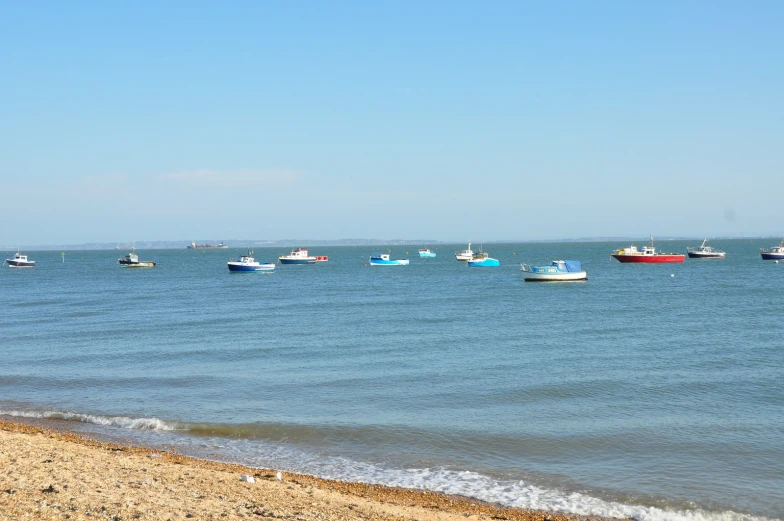 several small boats in the open water near the beach