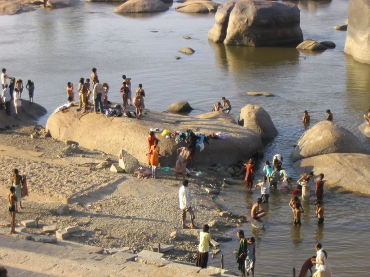 many people standing near a body of water on rocks