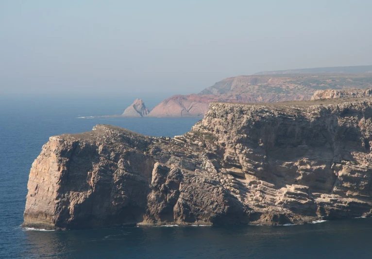 a mountain with a cliff face above it, and the ocean behind