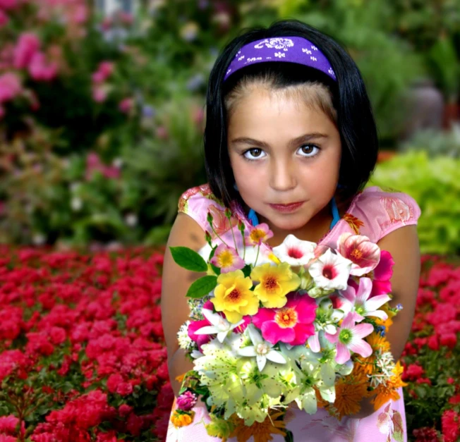 a little girl holding a bunch of flowers