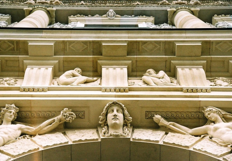 the front entrance to a building that has sculptures above and below it