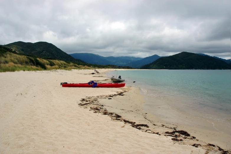 two kayaks are on a beach with mountains in the background