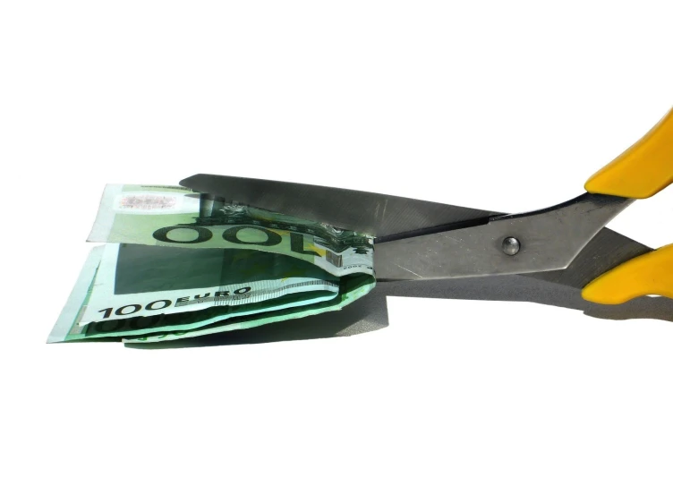 a pair of scissors is  through a hundred dollar bill