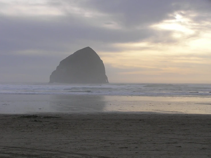 lone surfer standing on the beach in front of an island