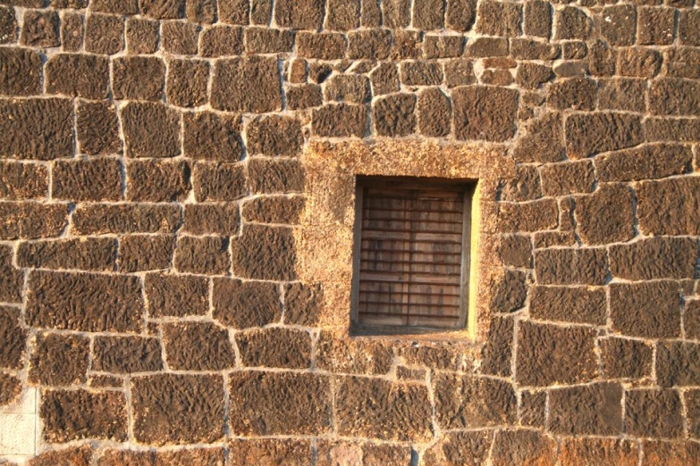 a stone structure with a window and bars on the outside