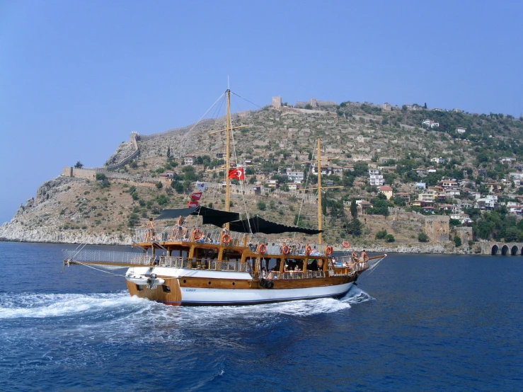 a large boat sails in the water by a mountain