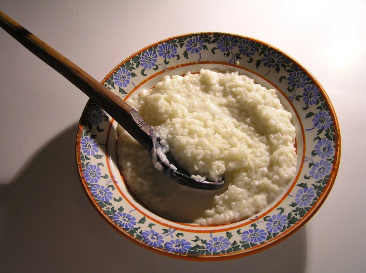 white mashed cauliflower in a colorful bowl with a spoon