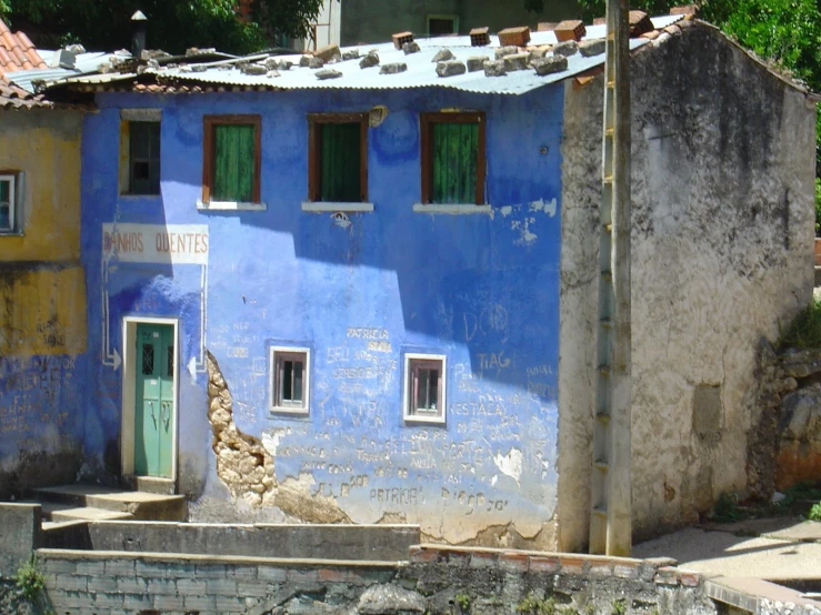 an old building with green doors has a blue paint job