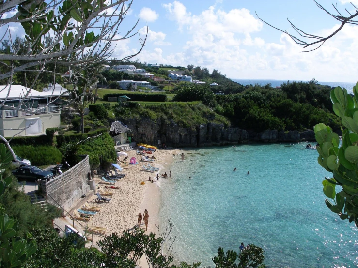 a beach with people walking around it and cars parked on the side