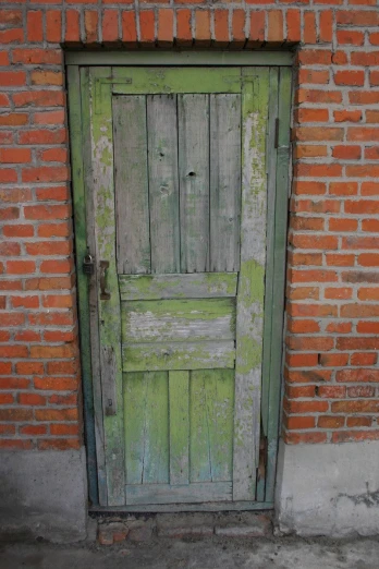 a green door stands open near brick wall