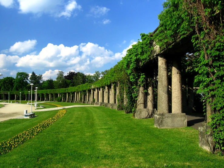 a line of pillars in a park with greenery