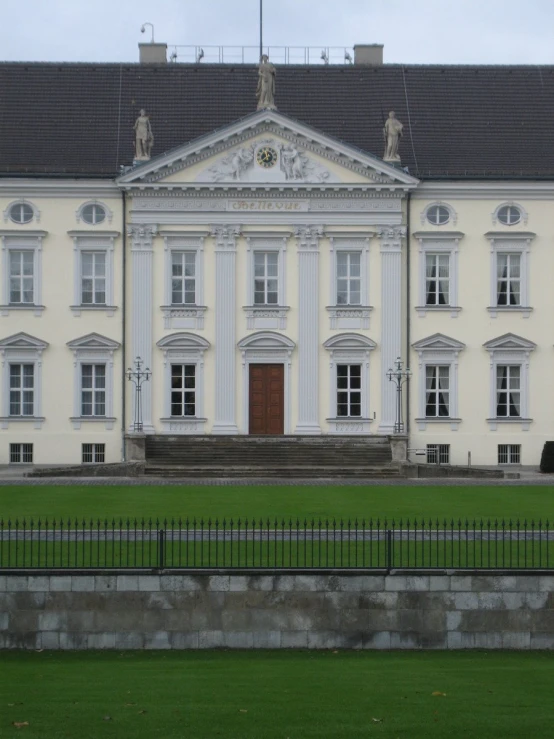 an ornately built white mansion with a black fence and steps leading up to it