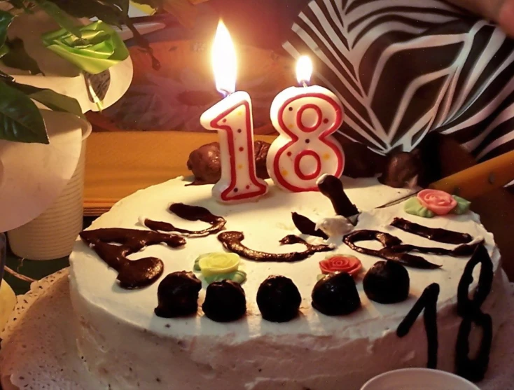 the cake is decorated with chocolate and has lit candles