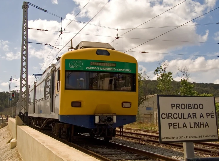 a yellow train is on the tracks under some wires