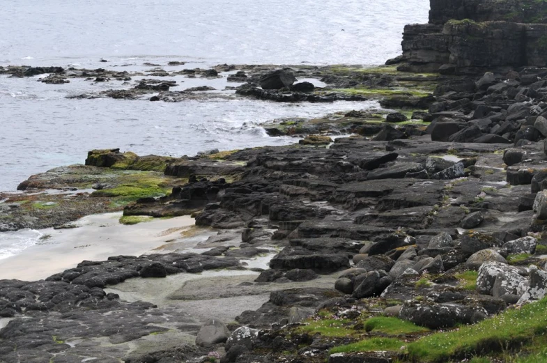 there is a man walking on the edge of a rocky shore