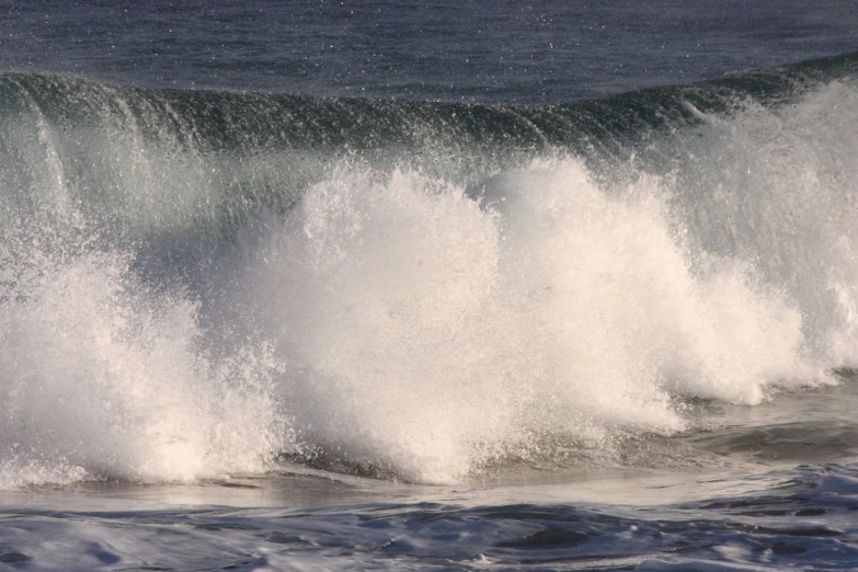 a large wave crashing on top of a blue ocean