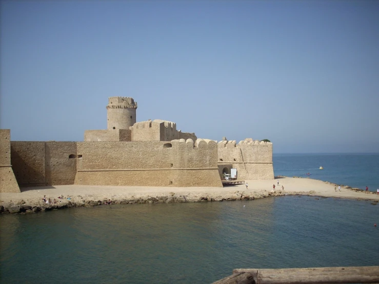 a boat sitting at the water's edge near a large stone wall