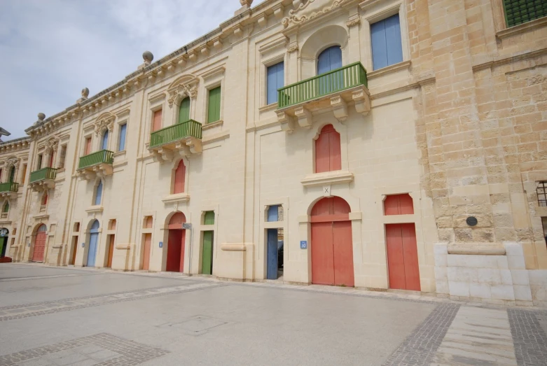 several windows, doors, and shutters in front of an old building