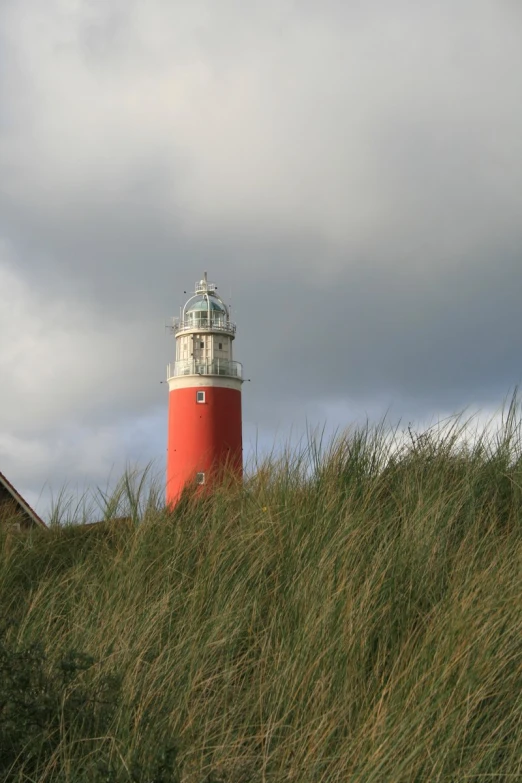 there is a red lighthouse sitting in tall grass