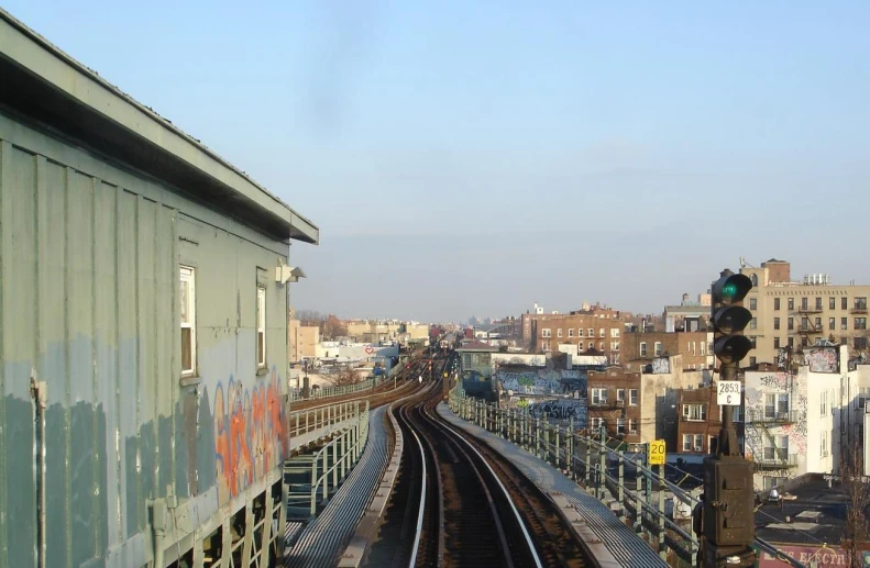 a train with graffiti passing by a city with high rise buildings