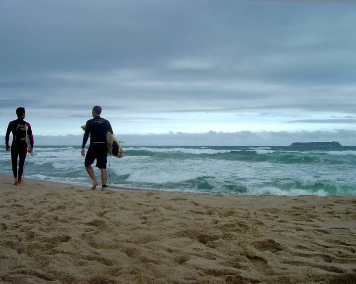 two people with surfboards standing on the beach