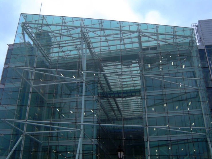large glass building with an iron scaffolding at the bottom