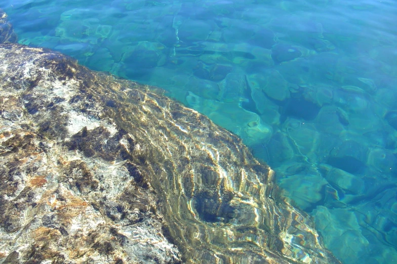 the water is blue and clear, a rock formation near a rock formation