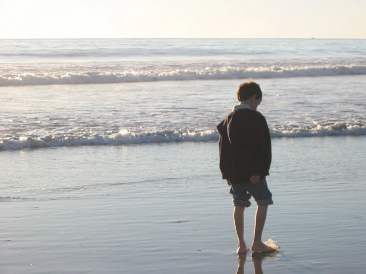 a man standing on top of a beach next to the ocean