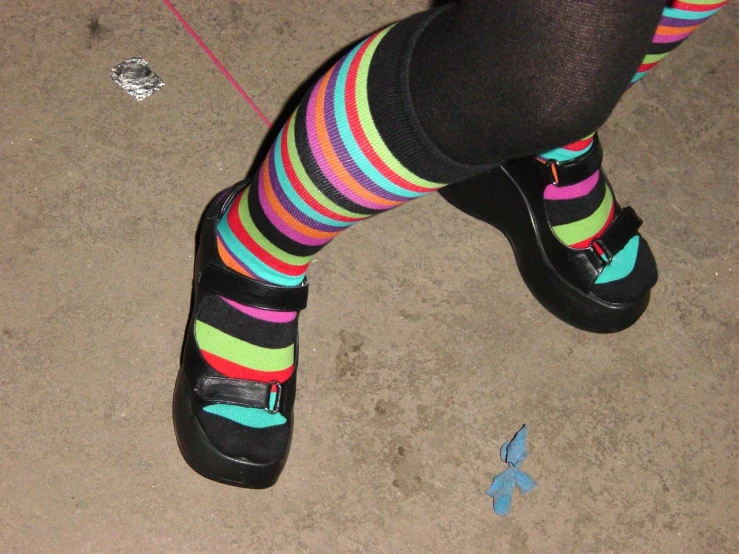 a girl with colorful socks stands near a broken glass