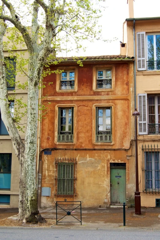 a large building with green doors sits next to a tree