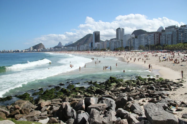 many people are walking along the beach on a clear day