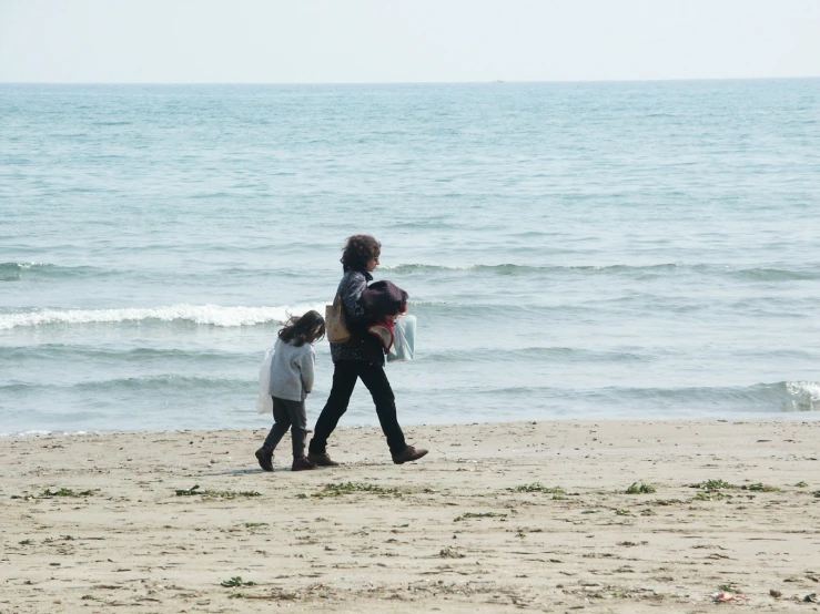 a couple of women walking along a sandy beach