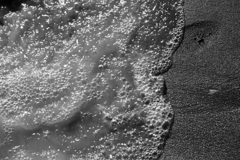 a black and white view of an ocean wave coming in to shore