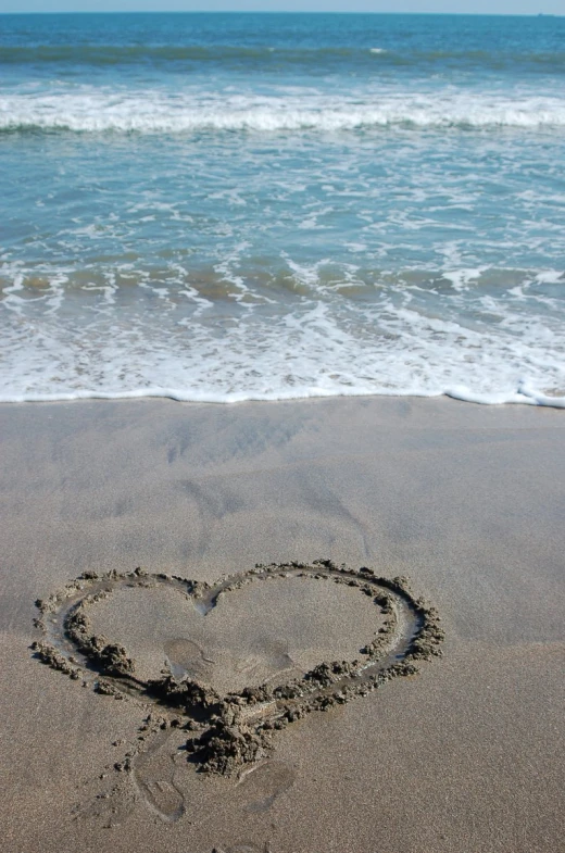 a heart drawn in the sand at the beach