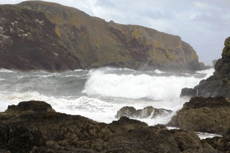 a rock cliff with waves crashing onto it