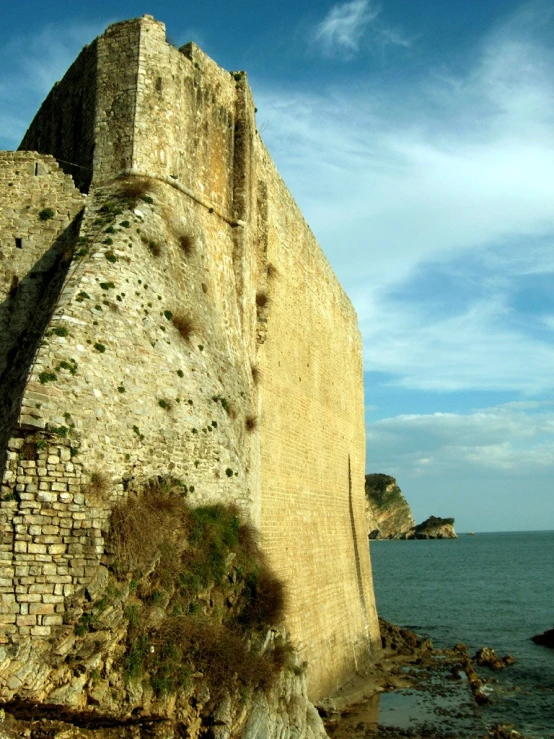 an old brick wall near water and rocks