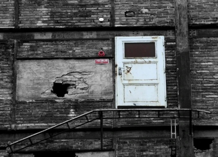 an old brick building has a rusted up door and steps