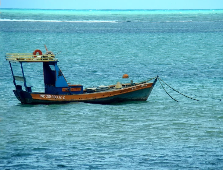 an old boat sitting in the ocean next to the shore