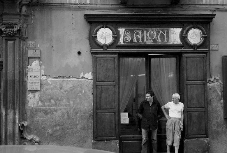 two people standing outside a doorway in front of an old building