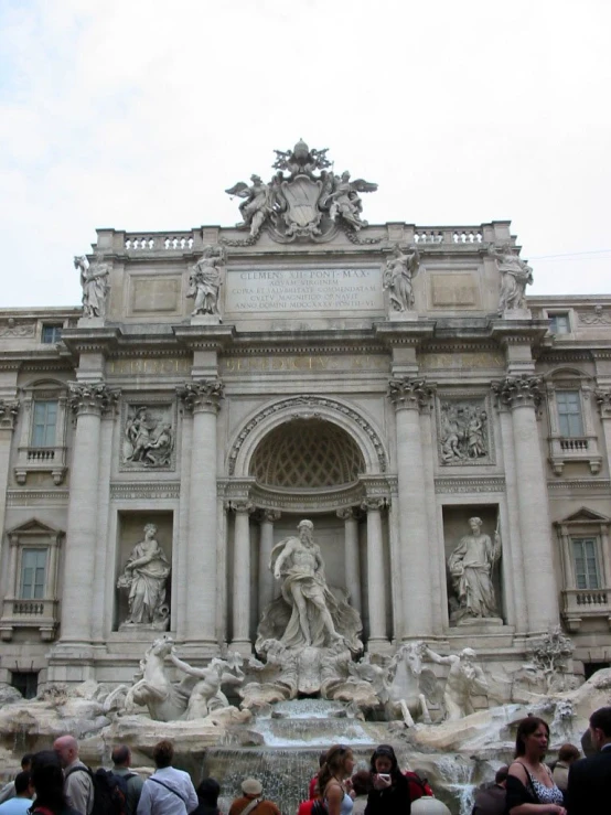 many people are standing in front of a fountain