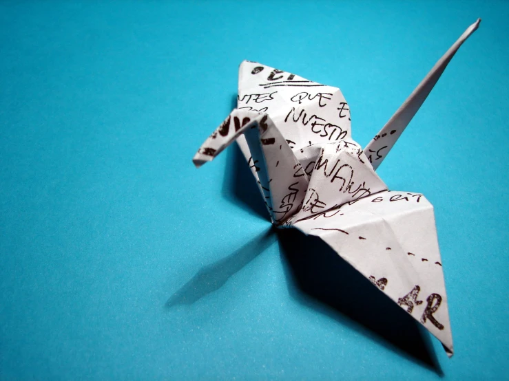 a paper crane with writing on it sitting on the ground