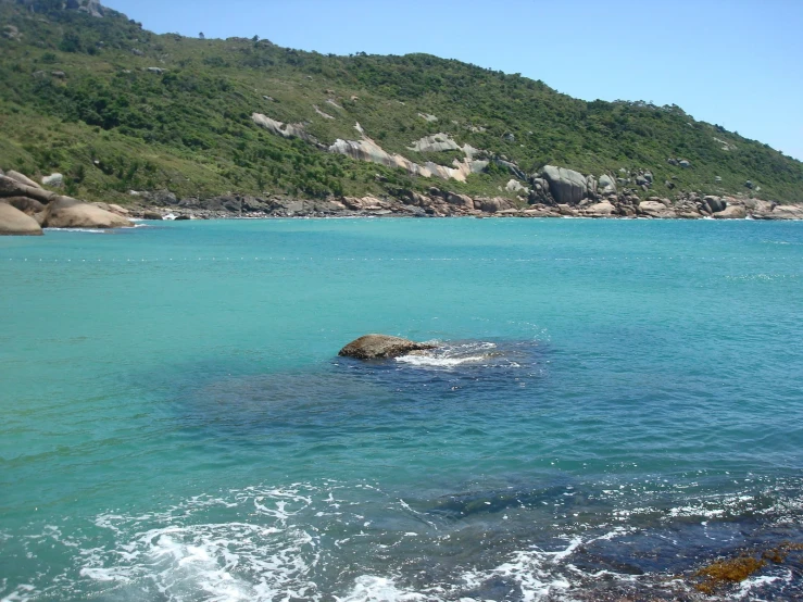 a body of water next to a green hillside