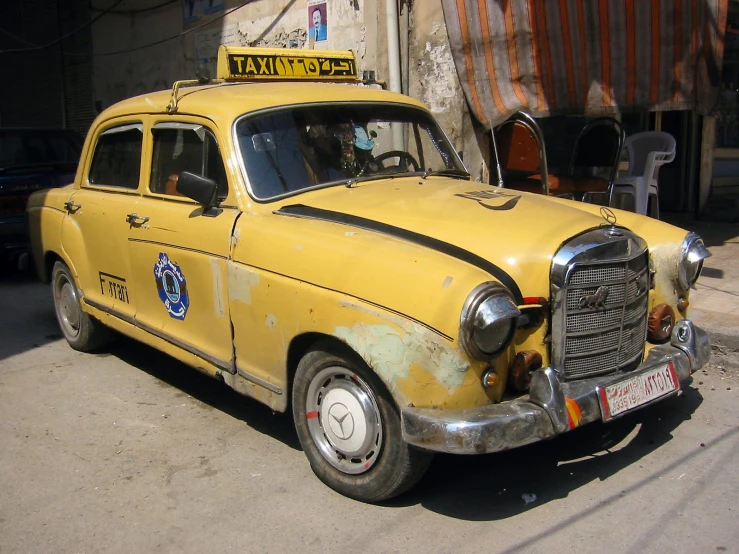 an old, abandoned yellow taxi is parked on the street
