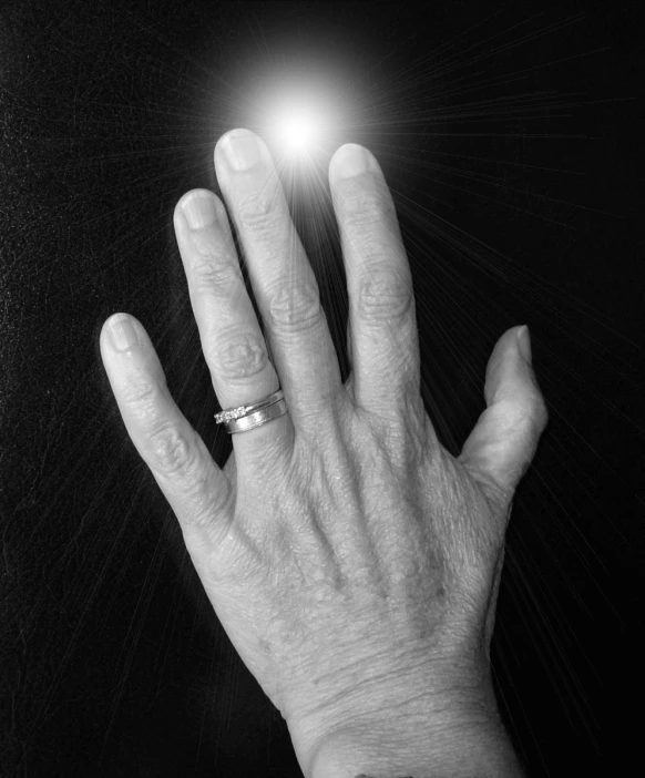 black and white image of a hand and a glowing ring