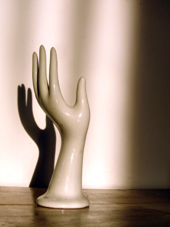 a hand sculpture stands near a wall