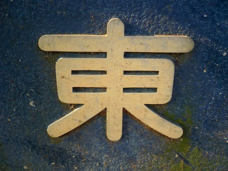 a metal sign in japanese writing on the ground