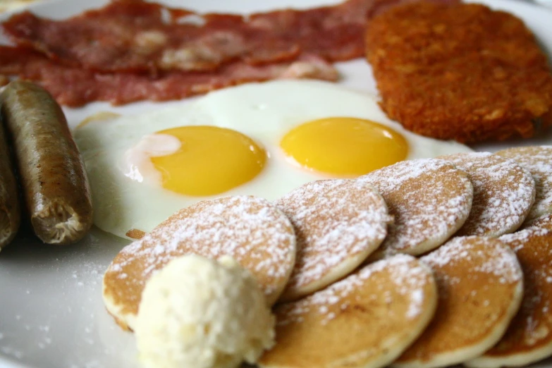 two eggs sitting next to a plate full of pancakes