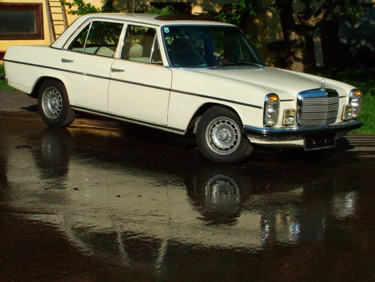 a vintage white station wagon parked in the rain